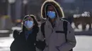 Sepasang suami istri mengenakan masker untuk membantu mengekang penyebaran virus corona berjalan melalui distrik perbelanjaan Wangfujing di Beijing, Minggu (12/12/2021).  (AP Photo/Andy Wong)