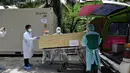 Pekerja memindahkan jenazah korban virus corona dari wadah (kontainer) berpendingin ke dalam peti mati di luar kamar mayat Rumah Sakit Thammasat, utara Bangkok, Rabu (4/8/2021). Thailand menjadi salah satu negara Asia Tenggara yang mengalami lonjakan kasus Covid-19. (Lillian SUWANRUMPHA/AFP)