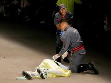 Petugas medis berusaha menyelamatkan model Tales Cotta saat terjatuh di catwalk Sao Paulo Fashion Week, Sao Paulo, Brasil, 27 April 2019. Model asal Brasil tersebut mendadak jatuh sakit dan meninggal saat mengikuti peragaan busana. (REUTERS/Leco Viana)