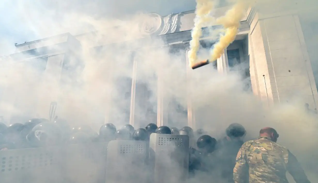Demonstran menyerang polisi dengan bom asap dan granat gas air mata di depan gedung Parlemen Ukraina , Senin (31/8). Satu petugas tewas dan 90 lainnya terluka dalam aksi yang menentang perubahan UU dasar mengenai desentralisasi. (AFP PHOTO/Genya SAVILOV)