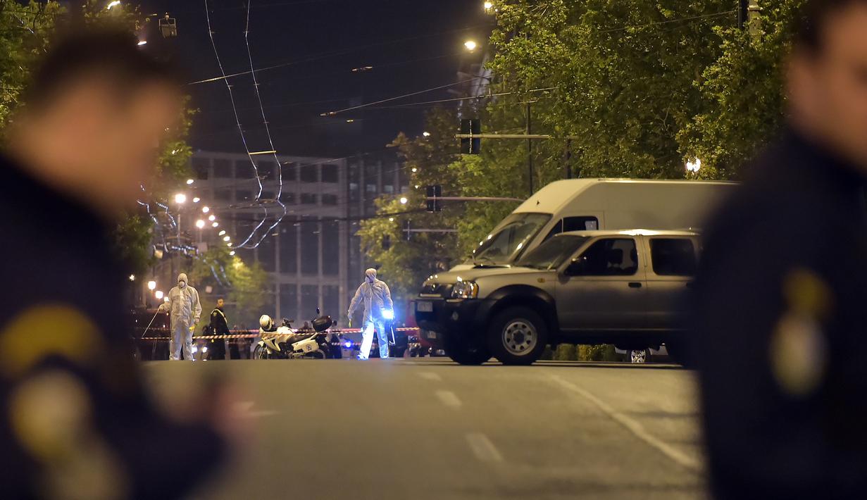 Polisi mengamankan area lokasi saat petugas forensik mencari bukti ledakan bom yang menghantam sebuah kantor cabang bank asal Yunani, Eurobank, di pusat Kota Athena, Rabu (19/4). Insiden ini mengakibatkan kantor tersebut hancur . (LOUISA GOULIAMAKI/AFP)