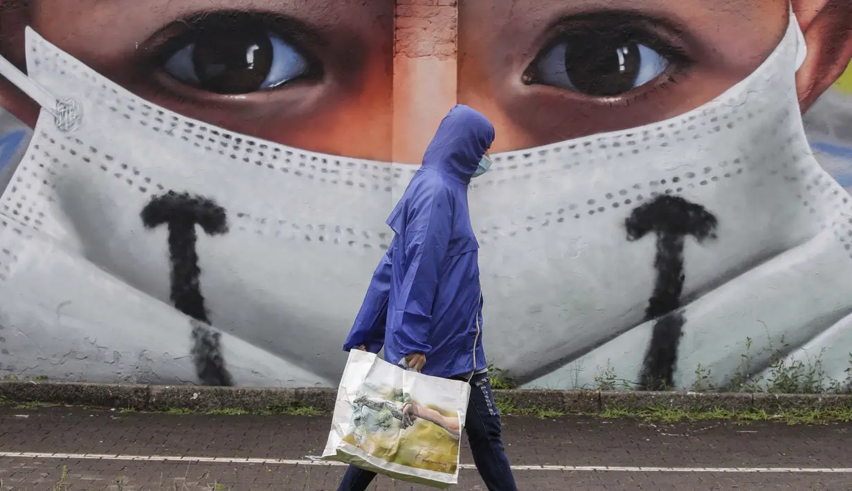 Seorang pria berjalan melewati sebuah lukisan dinding oleh seniman Cosimo Cheone yang didedikasikan untuk perawat rumah sakit Sacco, di Milan, Italia, pada 24 Juli 2020. (AP Photo / Luca Bruno)