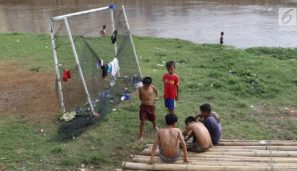 Anak-anak beristirahat usai bermain sepak bola di bantaran Kanal Banjir Barat, Jakarta, Jumat (5/4). Tidak adanya lapangan menjadikan lokasi tersebut sebagai tempat bermain mereka, meskipun dalam kondisi seadanya. (Liputan6.com/Immanuel Antonius)
