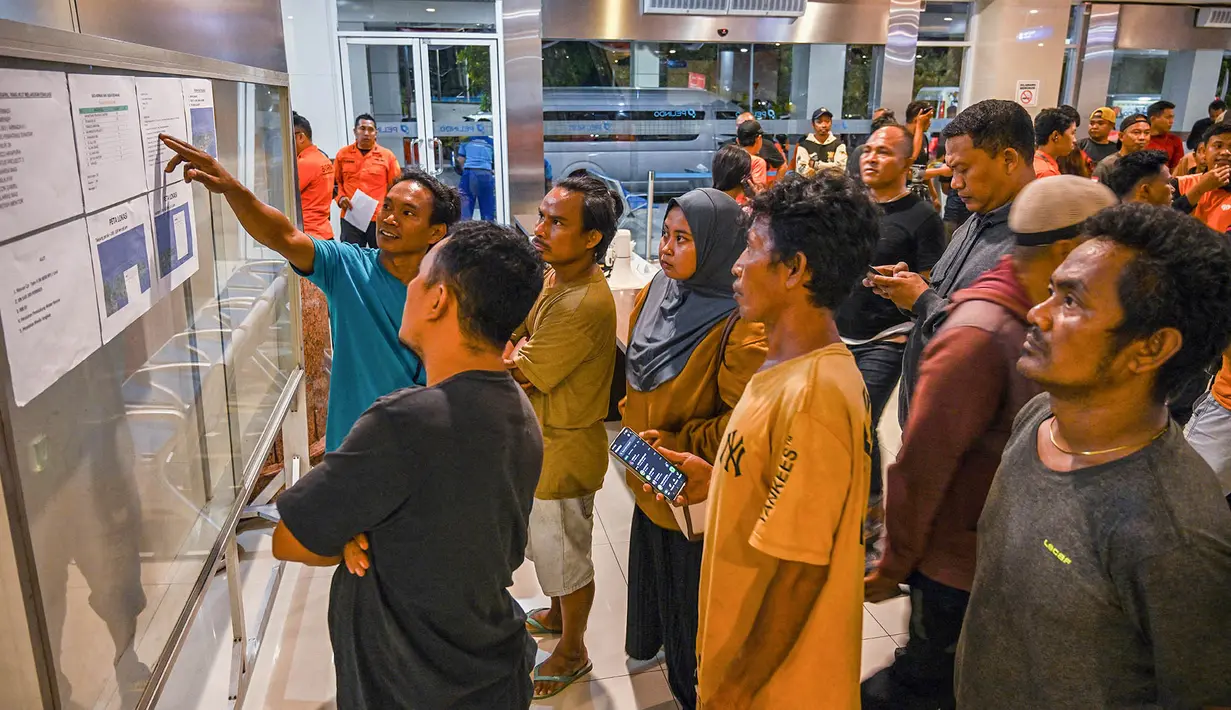 Keluarga korban berkumpul melihat papan informasi terkait penanganan peristiwa terbakarnya KM Mutiara Sentosa 2 di posko informasi, Gapura Surya Nusantara, Pelabuhan Tanjung Perak, Surabaya, Jawa Timur, Minggu (2/8/2026). (AFP/ Juni Kriswanto)