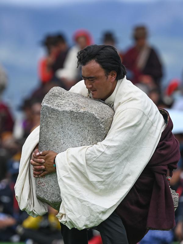 Seorang partisipan mengikuti kompetisi angkat batu yang digelar dalam festival balap kuda Dangjiren di Wilayah Damxung, Daerah Otonom Tibet, China barat daya, pada 11 Agustus 2020. (Xinhua/Purbu Zhaxi)