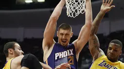 Aksi pemain Phoenix Suns, Alex Len, (tengah) saat melakukan dunk ditengah hadangan dua pemain Los Angeles Lakers pada laga NBA preseason basketball game di Anaheim, California (22/10/2016). (AP/Kelvin Kuo)