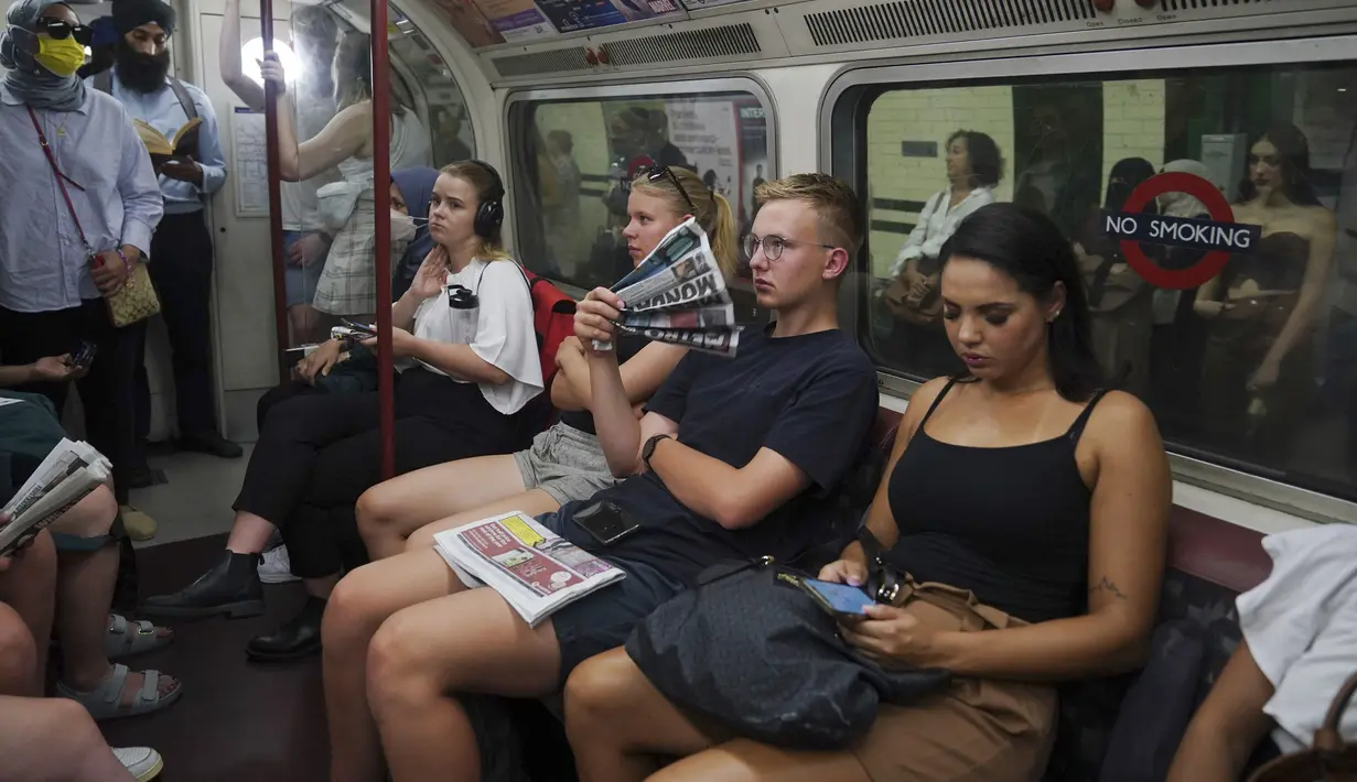 Seorang pria menggunakan koran sebagai kipas saat bepergian di jalur Bakerloo di London pusat selama gelombang panas, Senin (18/7/2022). Untuk pertama kalinya, Inggris mengalami cuaca panas dengan suhu diperkirakan mencapai 40 derajat celsius. (Yui Mok/PA via AP)
