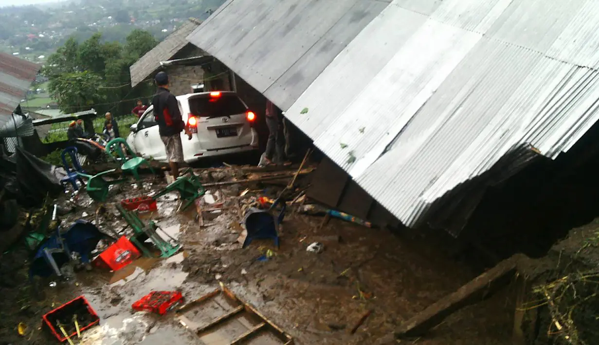 Warga mencari sisa-sisa barang yang bisa diselamatkan dari sebuah rumah yang ambruk akibat tanah longsor di Kecamatan Kintamani, Bali, Jumat (10/2). Sebanyak 12 orang dilaporkan meninggal akibat musibah ini. (STR/NATIONAL DISASTER AGENCY/AFP)