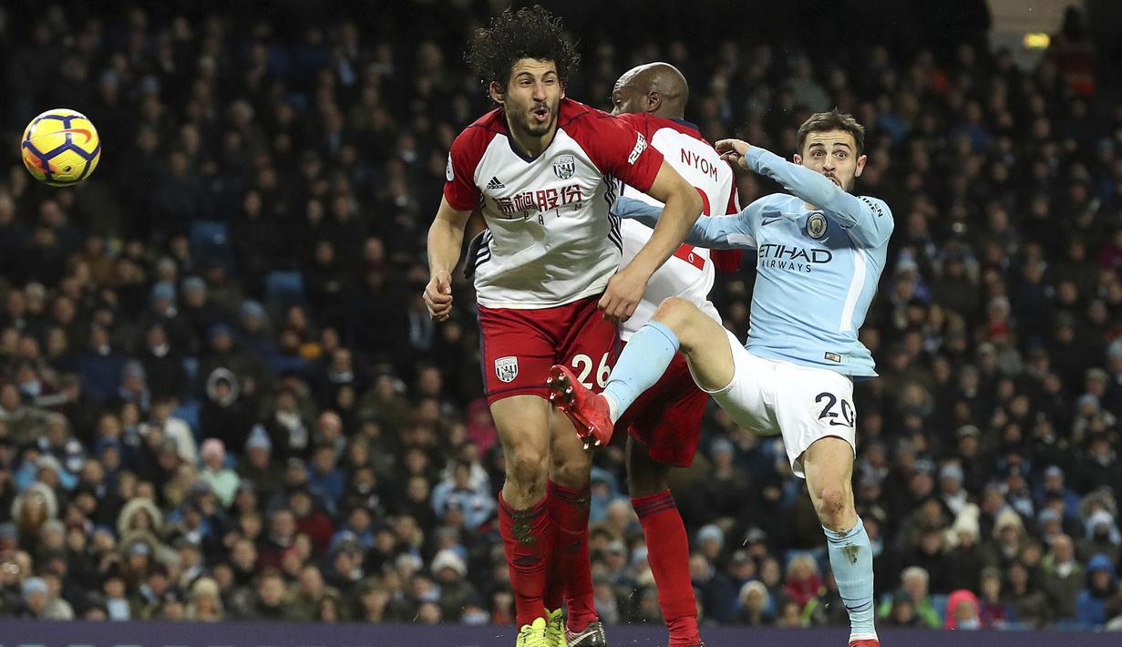 Pemain West Bromwich, Ahmed Hegazi (kiri) berebut bola dengan pemain Manchester City, Bernardo Silva pada lanjutan Premier League di The Etihad Stadium, Manchester, (31/1/2018). Manchester City menang 3-0. (Martin Rickett/PA via AP)