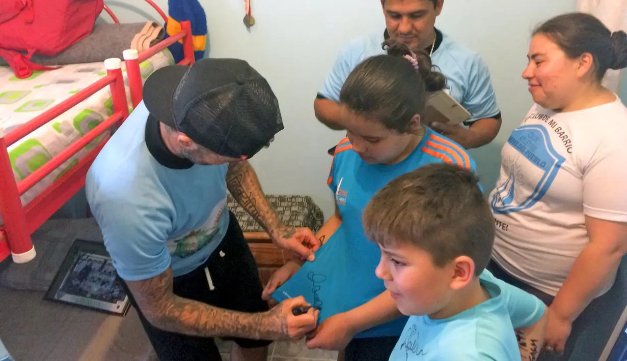 Bintang Sepak Bola David Beckham memberikan tanda tangan usai bermain bola dengan anak-anak untuk pembuatan film Dokumenter di Buenos Aires, Senin (9/11/2015).  (AFP Photo/FIXER-ARGENTINA/Macarena Galiardi)