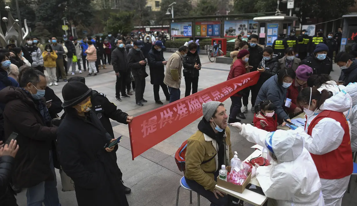 Seorang warga asing di antara warga mengantre untuk mengambil sampel usap tenggorokan selama tes COVID-19 massal di sebuah kompleks perumahan di Wuhan di provinsi Hubei, China tengah, Selasa (22/2/2022). (Chinatopix via AP)