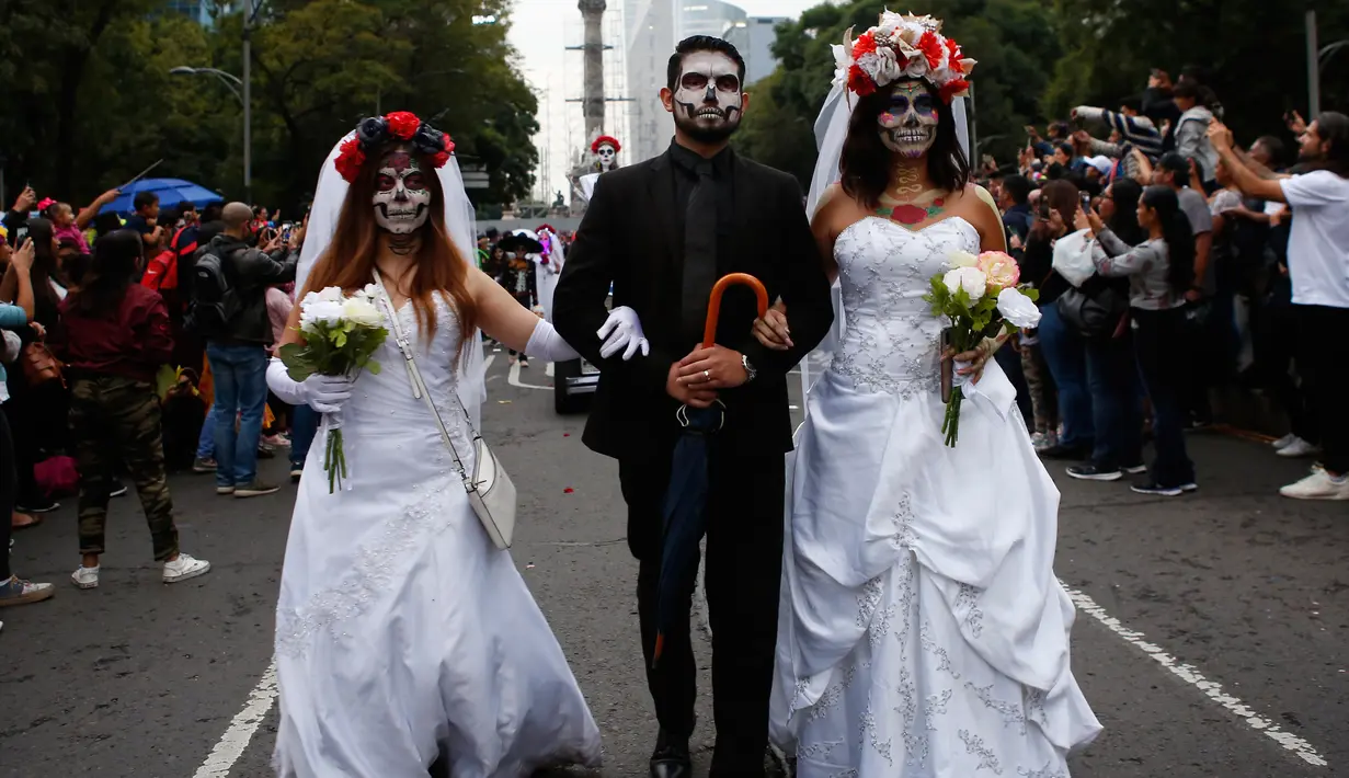 Peserta berdandan ala tengkorak saat mengikuti parade Hari Orang Mati di Mexico City, Meksiko, Sabtu (26/10/2019. Para peserta dalam parade ini mengenakan kostum dan melukis wajah mirip dengan tokoh tengkorak Meksiko yang ikonik, Catrina. (AP Photo/Ginnette Riquelme)