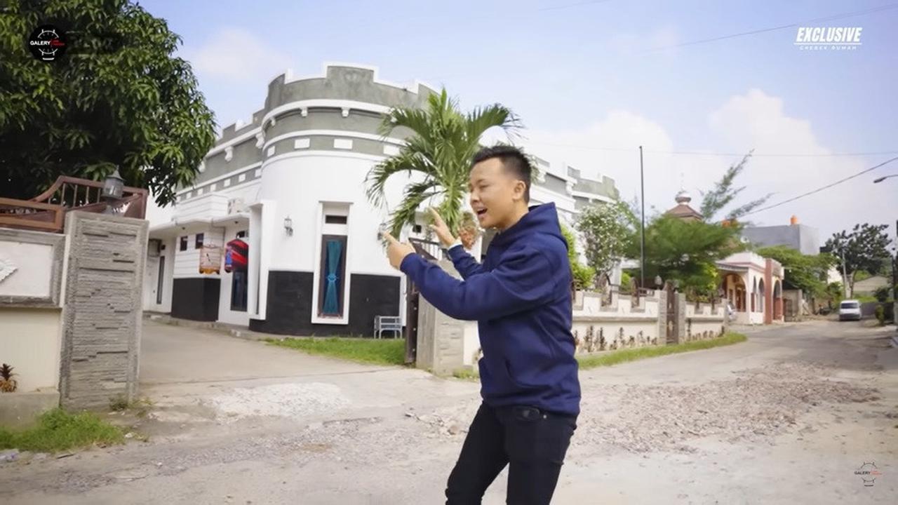 Dari jalan yang aspalnya sedikit mengelupas, terlihat bagian depan rumah Andika yang melengkung seperti kastil atau sebuah benteng.