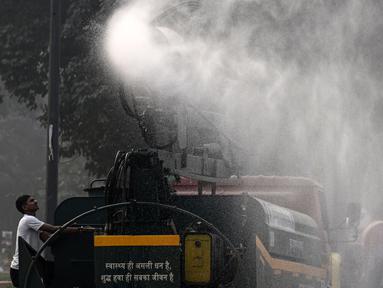 Sebuah kendaraan dari Departemen Pekerjaan Umum (PWD) menyemprotkan air dengan menggunakan penyemprot anti-kabut asap untuk mengurangi polusi udara di New Delhi, India pada 7 November 2024. (Arun SANKAR/AFP)
