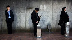 Warga saat merokok di smoking area yang disediakan di Naka-Meguro, Tokyo (10/3). Jepang adalah salah satu negara yang memberlakukan aturan ketat bagi para perokok di tempat umum. (AFP Photo/BEHROUZ MEHRI)