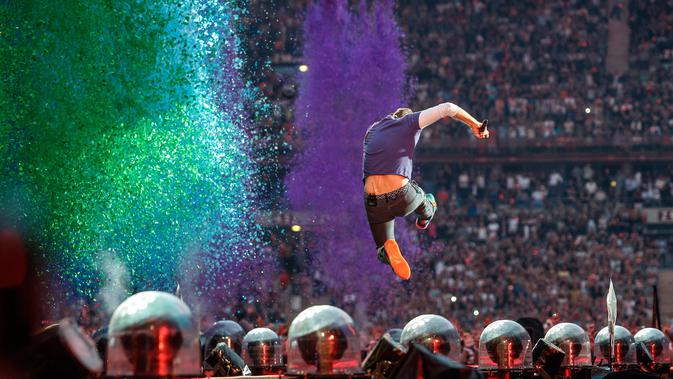 Aksi panggung Chris Martin yang melompat saat tampil di The Stade de France Arena di Saint Denis, Paris, Prancis (15/7). (AFP Photo/Geoffroy Van Der Hasselt)
