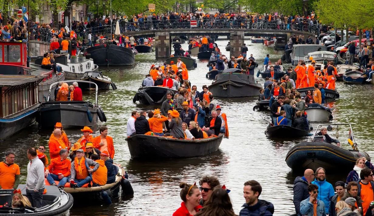 Warna nasional Belanda, oranye, mendominasi kanal saat Hari Ulang Tahun Raja atau King's Day di Amsterdam, 27 April 2018. Pada Hari Raja, masyarakat mengenakan pakaian berwarna oranye, bahkan sering kali mengenakan wig atau riasan oranye (AP/Peter Dejong)