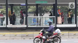 Sejumlah pekerja menunggu bus saat jam pulang kerja di halte Bundaran Senayan, Jakarta, (3/11/2021). Mobilitas masyarakat di Ibu Kota semakin meningkat seiring dilonggarkannya beberapa aturan. (Liputan6.com/Herman Zakharia)