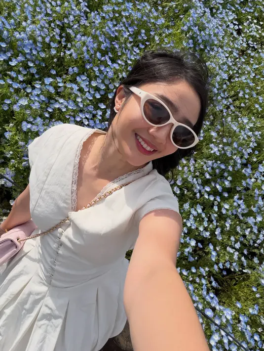 Febby juga tampil lebih manis dengan sleeveless dress putih beraksen lace pada bagian neckline. Dress bernuansa flowy itu memberi kesan feminin sekaligus fresh saat dipadukan sunglasses putih cat-eye. [@febbyrastanty].