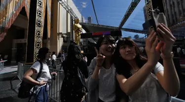 Wisatawan berselfie dengan patung Oscar di luar Teater Dolby selama persiapan jelang 88 Academy Awards di Hollywood, California (24/2). Piala Oscar merupakan penghargaan film Amerika untuk menghargai suatu karya industri film. (REUTERS/Mario Anzuoni)