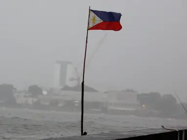 Bendera Filipina berkibar di dekat seorang warga yang memancing ditengah cuaca buruk akibat Topan Nepartak yang menerpa di Manila Bay, Filipina, Jumat (8/7). (REUTERS/Erik De Castro)