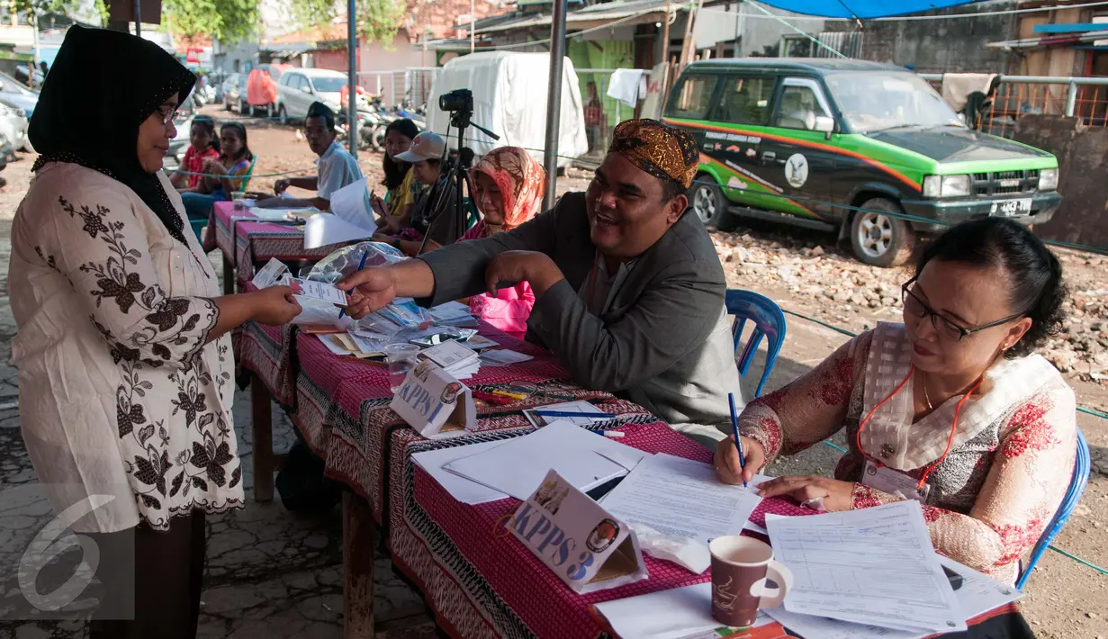 Petugas KPPS mengenakan pakaian adat dan belangkon melayani warga untuk menggunakan hak pilih di TPS 14 Cipinang Besar Selatan, Jakarta, Rabu (19/4). (Liputan6.com/Gempur M. Surya)