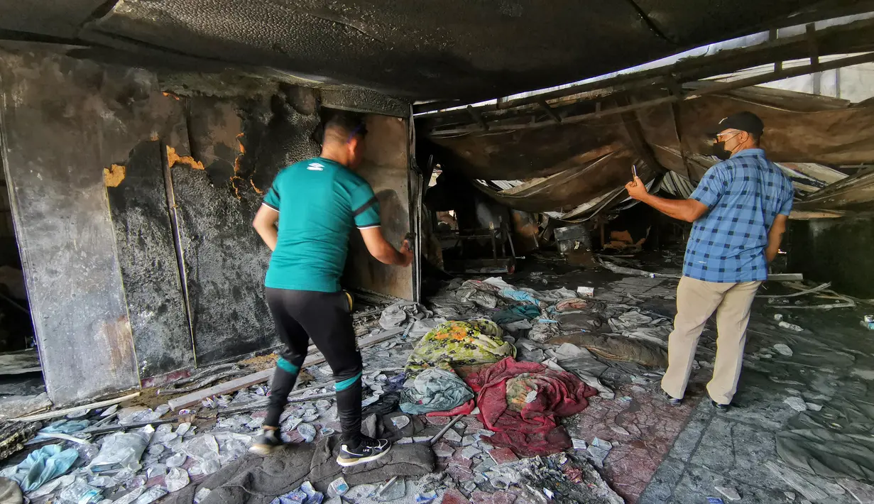 Orang-orang mengambil gambar bangsal isolasi COVID-19 yang porak-poranda di rumah sakit Al-Hussein setelah kebakaran besar di kota Nasiriyah, Irak, Selasa (13/7/2021). Kebakaran rumah sakit rujukan Covid-19 itu mengakibatkan setidaknya 52 orang tewas dan sejumlah lainnya luka-luka. (Asaad NIAZI/AFP)