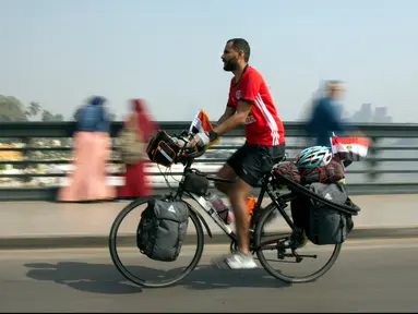 Seorang pria Mesir, Mohammed Nufal (24) mengendarai sepedanya melintasi jembatan Qasr El-Nile di Kairo, Sabtu (7/4). Nufal mengayuh sepedanya sejauh 5000 kilometer menuju Rusia, demi mendukung timnas Mesir di Piala Dunia 2018. (AP/Amr Nabil)