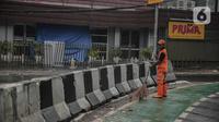 Petugas PPSU membersihkan sampah dekat beton pembatas di Jalan Senopati, Jakarta, Minggu (29/12/2019). Pascakejadian mobil tabrak Apotek Senopati, Suku Dinas Bina Marga memasangan beton pembatas untuk meminimalisir kejadian serupa terulang kembali. (Liputan6.com/Faizal Fanani)