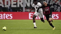 Bek AC Milan, Sergino Dest berlari berebut bola dengan pemain Torino, Stephane Singo pada pertandingan babak 16 besar Coppa Italia di Stadion San Siro di Milan, Italia, Kamis (12/1/2023). Torino menang tipis atas AC Milan dengan skor 1-0 berkat gol Michel Adopo di perpanjangan waktu. (Marco Alpozzi/LaPresse via AP)