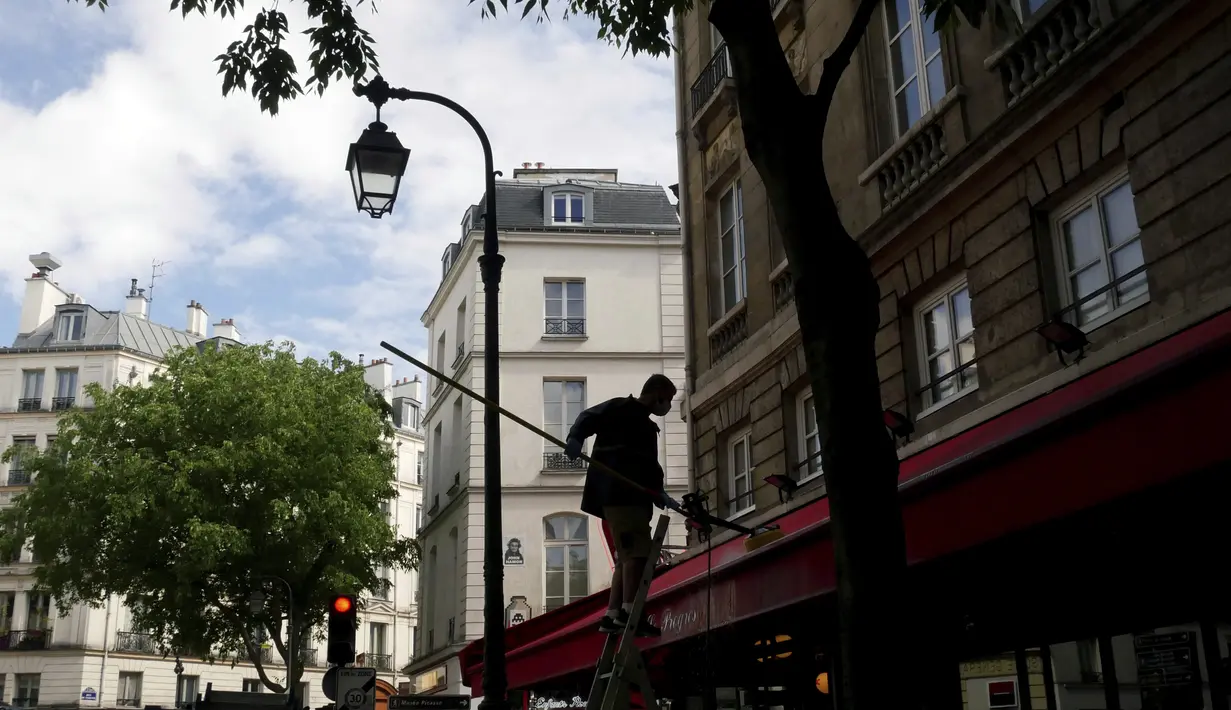 Seorang pekerja membersihkan tenda sebuah restoran, di Paris, Senin (17/5/2021). Teras luar kafe dan restoran Prancis akan diizinkan untuk dibuka kembali pada 19 Mei bersama dengan museum, bioskop, teater, dan ruang konser dalam kondisi tertentu. (AP Photo/Thibault Camus)