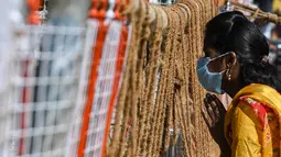 Seorang jemaah berdoa dari sebelah barikade yang ditempatkan di depan sebuah kuil, setelah tempat ibadah keagamaan ditutup untuk umum untuk mengekang lonjakan virus corona Covid-19 sesuai arahan pemerintah negara bagian di Chennai (7/1/2022). (AFP/Arun Sankar)