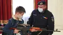 Seorang anak laki-laki memegang senjata di stand yang didirikan oleh gendarmerie Rumania di Istana Parlemen pada Hari Anak Internasional di Bukares, Rumania, Selasa (1/6/2021). Orang-orang memanfaatkan kesempatan untuk mengunjunginya secara gratis. (AP Photo/Vadim Ghirda)
