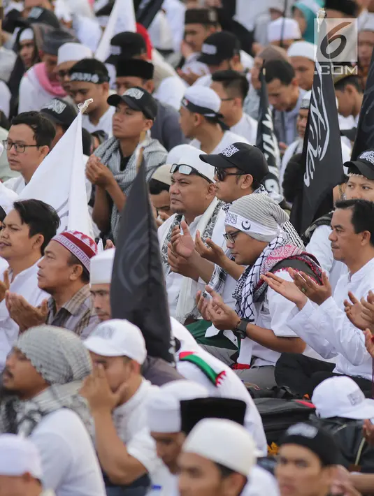 Umat muslim berdoa bersaat saat mengikuti aksi reuni 212 di kawasan silang Monas, Jakarta, Minggu (2/12). Bendera dan panji-panji terlihat diusung para peserta aksi reuni akbar 212. (Liputan6.com/Herman Zakharia)