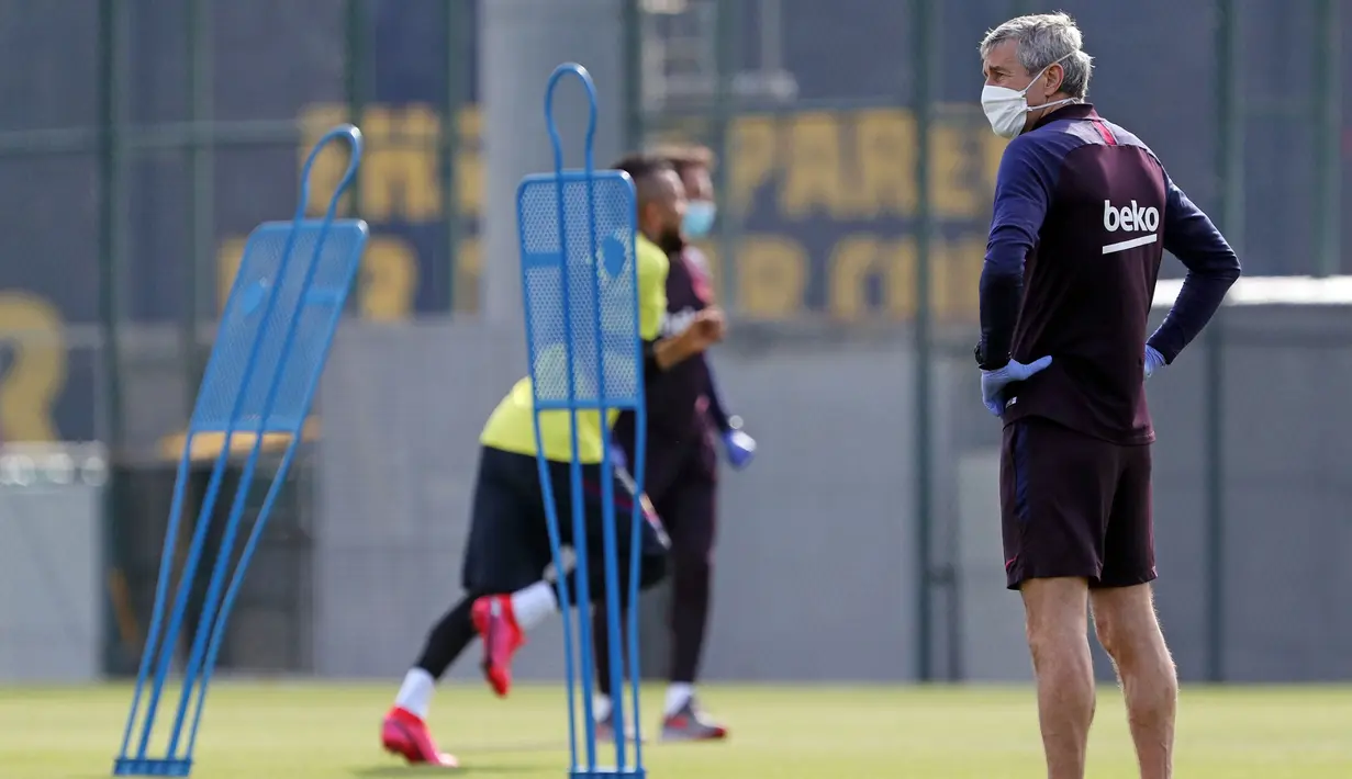 Pelatih Barcelona, Quique Setien, memperhatikan pemainnya saat sesi latihan di Ciutat Esportiva Joan Gamper, Sant Joan Despi, Jumat (8/5/2020) waktu setempat. Barcelona kembali menjalani latihan usai seluruh pemain tim utama dinyatakan negatif COVID-19. (AFP/Miguel Ruiz)