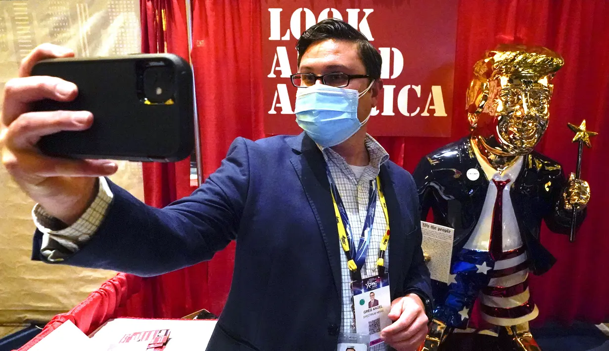 Seorang peserta berswafoto dengan patung emas Donald Trump pada Konferensi Politik Konservatif (CPAC) di Orlando, Florida, Jumat (26/2/2021). Patung setinggi lebih dari 6 kaki ciptaan seniman Tommy Zegansebagai tanggapan atas berbagai karya seni yang mengejek Trump. (AP Photo / John Raoux)