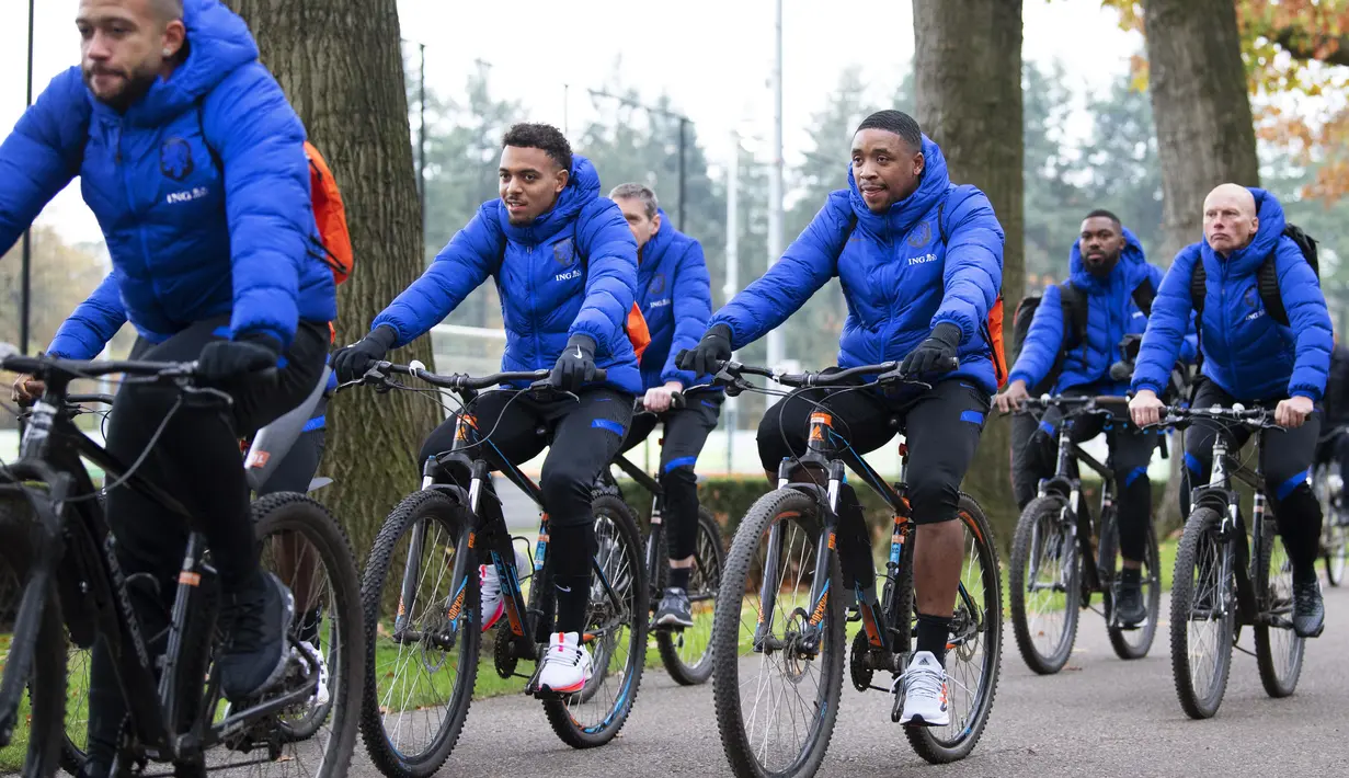 Pemain depan Belanda Donyell Malen (kedua kiri) dan Steven Bergwijn (tengah) bersama rekan setimnya mengendarai sepeda selama sesi latihan tim di Kampus KNVB di Zeist (10/11/2021). Belanda akan bertanding melawan Montenegro pada Kualifikasi Piala Dunia 2022. (AFP/ANP/Olaf Kraak)