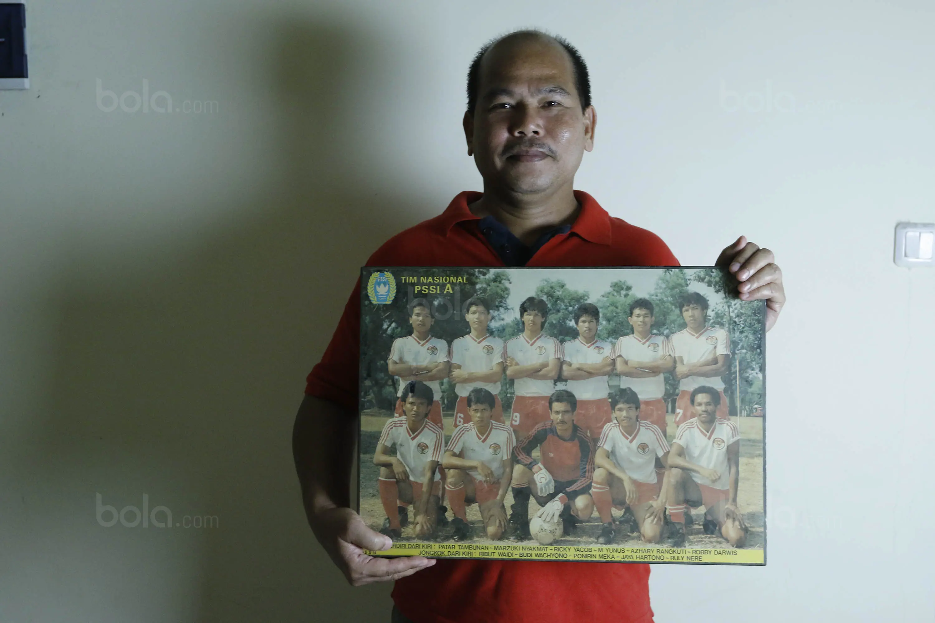 Mantan gelandang Timnas Indonesia, Patar Tambunan, memegang foto Timnas Indonesia saat ditemui di kawasan Bintaro, Selasa (01/8/2017). Patar Tambunan adalah salah satu anggota Timnas Indonesia pada Games 1987. (Bola.com/M Iqbal I