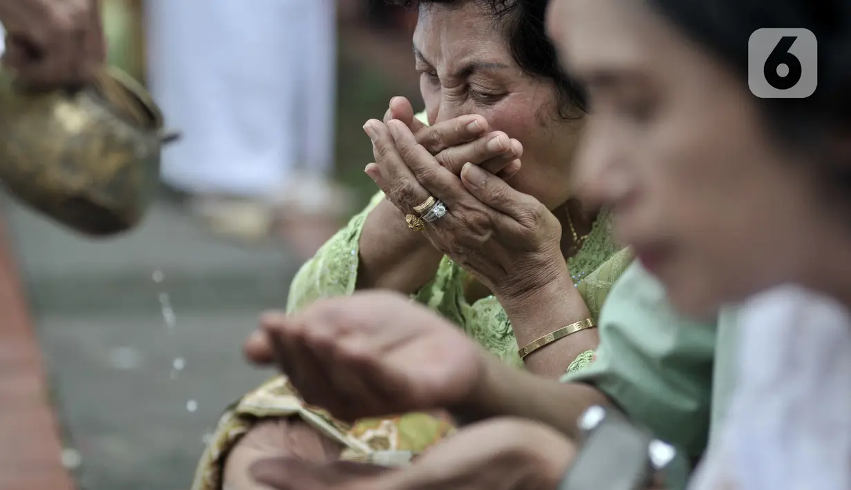 Umat Hindu meminum Tirta (air suci) saat persembahyangan Hari Raya Galungan di Pura Aditya Jaya, Rawamangun, Jakarta, Rabu (19/2/2020). Hari Raya Galungan yang merupakan hari kemenangan kebenaran (Dharma) atas kejahatan (Adharma) itu dirayakan setiap 210 hari sekali. (merdeka.com/Iqbal Nugroho)