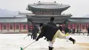 Pekerja membersihkan salju di istana Gyeongbokgung setelah salju turun Seoul, Korea Selatan (15/2). Istana ini hancur pada saat invasi Jepang ke Korea tahun 1592-1598dan dibangun lagi selama tahun 1860-an. (AFP Photo/Jung Yeon-je)