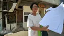 Seorang ibu penguni rumah menunjukan surat Hak Guna Bangunan ketika petugas melakukan penertiban terhadap rumah miliknya, tepat di samping Kantor Kelurahan Rawajati, Pancoran, Jakarta, Selasa (22/12). (Liputan6.com/Yoppy Renato)