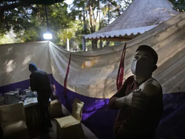 Reaksi seseorang ketika menunggu setelah menerima vaksin COVID-19 di sebuah pasar di New Delhi, Rabu (29/12/2021). Di India, yang telah kembali normal setelah dihantam tsunami COVID-19 tahun ini, omicron sekali lagi menimbulkan ketakutan, dengan lebih dari 700 kasus dilaporkan. (AP Photo/Manish Sw