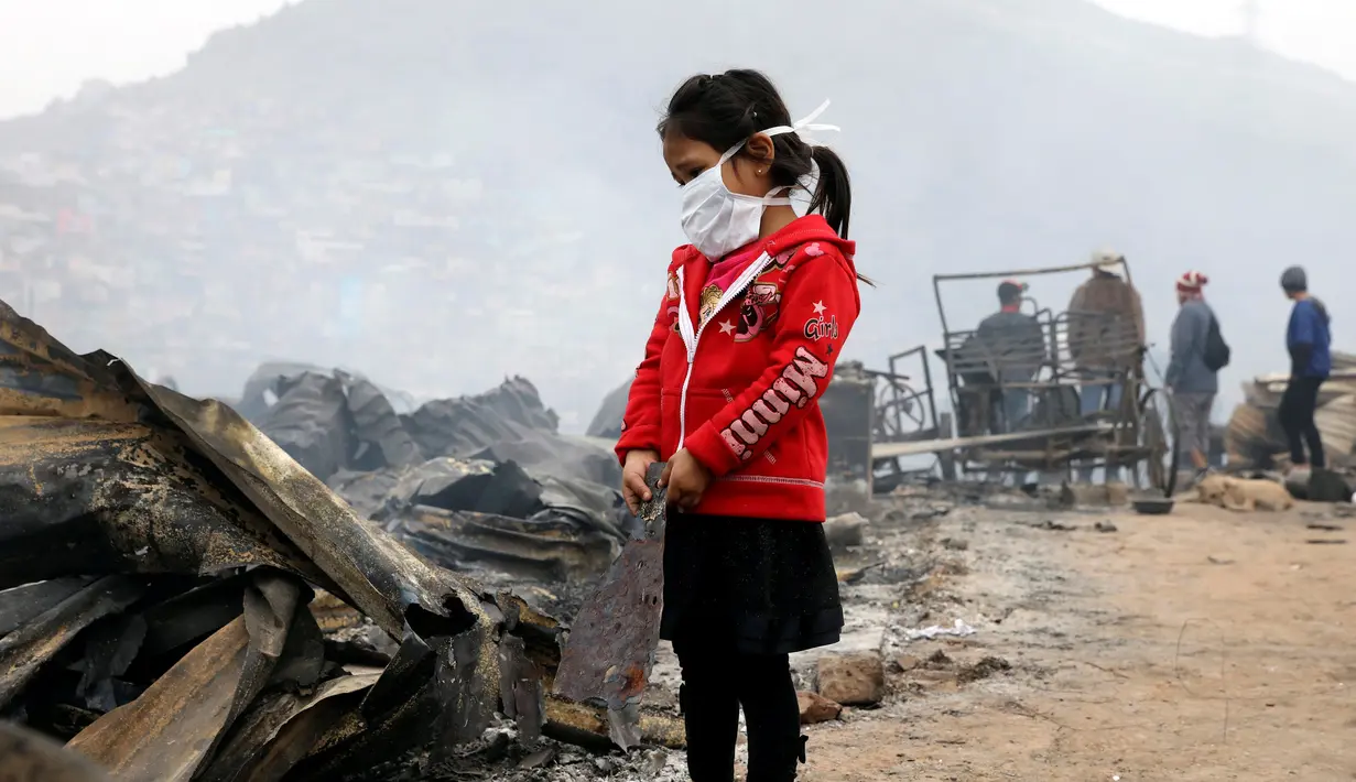 Seorang anak berdiri di lokasi kebakaran besar yang melanda permukiman Cantagallo di Lima, Peru, Jumat (4/11). Dilaporkan, permukiman yang terbakar itu dihuni oleh komunitas Suku Amazon yang tinggal di Lima. (REUTERS/Guadalupe Pardo)