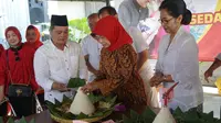 Ibunda Presiden Jokowi sedang memotong nasi bancakan selapanan Sedah Mirah Nasution di Solo, Selasa (11/9).(Liputan6.com/Fajar Abrori)