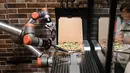 Foto pada 1 Juli 2021 menunjukkan "Pazzi", robot pembuat pizza sedang bekerja di sebuah restoran di Paris. Restoran kecil Pazzi di distrik Beaubourg adalah yang kedua dibuka, setelah di pusat perbelanjaan Val d'Europe yang dibuka pada November 2019 lalu. (BERTRAND GUAY/AFP)