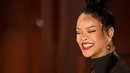 Senyum Rihanna saat menghadiri Academy Awards ke-95 atau Oscar 2023 di Teater Dolby di Hollywood, California pada Minggu, 12 Maret 2023, waktu setempat. Rihanna menata rambutnya dengan high top knot bun dengan untaian rambut yang menjuntai. (Photo by Robyn BECK / AFP)
