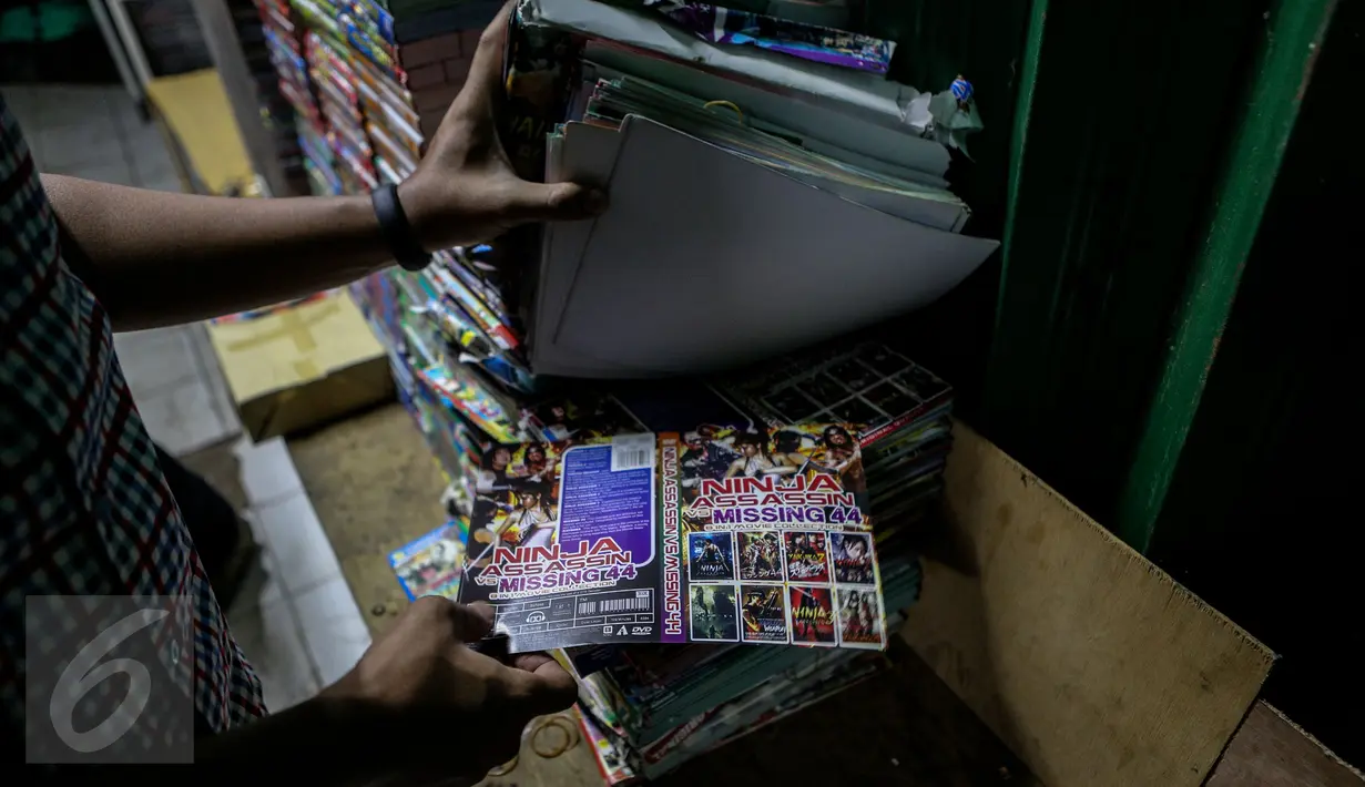 Petugas menunjukkan kaset bajakan saat melakukan razia di Plaza Glodok, Jakarta, Rabu (24/6). Razia dilakukan karena pabrik sekaligus tempat penjualan DVD terbesar di DKI Jakarta itu masih beroperasi selama Ramadan. (Liputan6.com/Faizal Fanani)