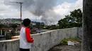 Seorang warga melihat kepulan asap di dekat rumahnya, usai pesawat tempur militer Filipina melancarkan serangan ke kawasan yang telah di kuasai militan Maute di kota Marawi di Filipina Selatan, (27/5). (AP Photo / Bullit Marquez)