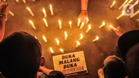 Massa yang tergabung dalam Ultras Garuda Jakarta mengikuti aksi menyalakan lilin dan tabur bunga untuk korban kerusuhan Stadion Kanjuruhan Malang di depan Stadion Gelora Bung Karno (GBK), Jakarta, Minggu (2/10/2022). Aksi tersebut sebagai aksi solidaritas antar suporter dan bentuk keprihatinan atas tragedi kerusuhan suporter sepak bola di Stadion Kanjuruhan Malang. (merdeka.com/Iqbal S Nugroho)