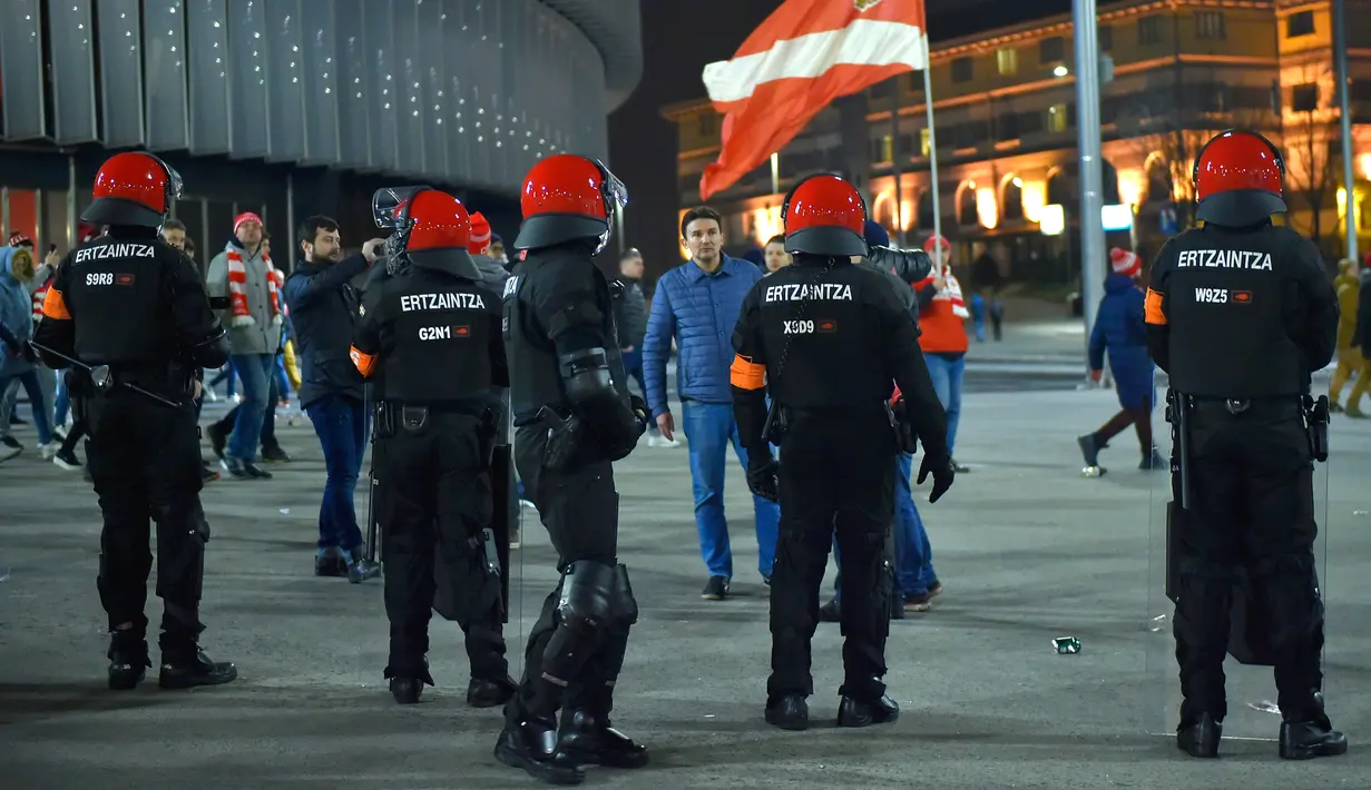 Seorang suporter Spartak Moskow berjalan melewati polisi di Stadion San Mames, Bilbao, Spanyol, Kamis (22/2). Polisi Inocencio Arias Garcia meninggal dunia karena mengalami serangan jantung saat bentrok. (ANDER GILLENEA/AFP)